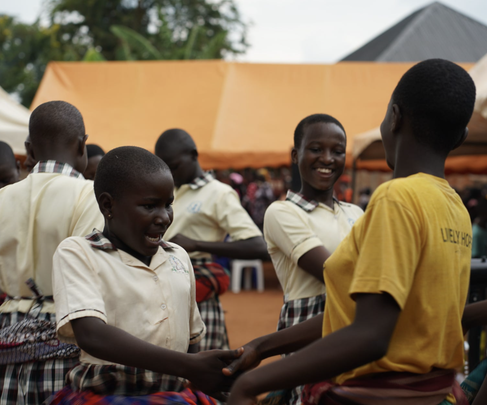 Schoolchildren holding hands in a circle at a village gathering